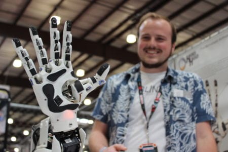 Researcher Dylan Brenneis waves hello with the 3-D printed prosthetic arm he created.